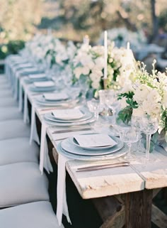 the table is set with white flowers and place settings