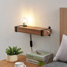 a wooden shelf with a light on top of it next to a book and coffee cup