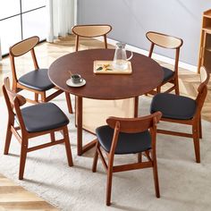 a dining table with four chairs and a tray on the top, in front of a window