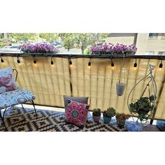 a balcony with plants and chairs on the floor next to a window covered in blinds