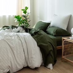 an unmade bed with green and white striped comforter, pillows and pillowcases