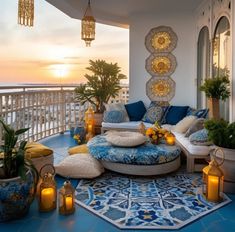 an outdoor living area with blue and white furniture, potted plants and candles on the floor