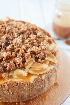 an apple crumble cake sitting on top of a wooden plate with caramel sauce