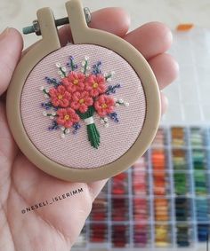 a hand holding a small embroidery kit with flowers on it