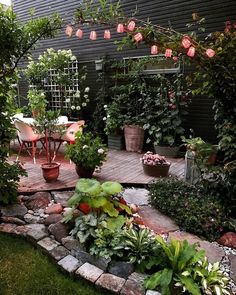 an outdoor patio with potted plants and flowers on the decking area, surrounded by greenery