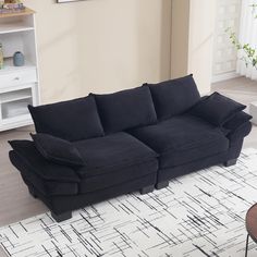 a black couch sitting on top of a white rug