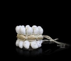 A handwoven white braided rope wide bracelet, decorated with two bands of white curled Shells, a band of cream Cowrie Shells, and a central band of golden round beads. The inner diameter of the bracelet is 2 inches, and the bracelet is 2.1 inches in width. The bracelet is attached by two groups of two, 7.5 inches white cord strands (for adjustable sizing), each decorated at the end with a silver round bead. ► Find these in more dazzling colors here: https://www.etsy.com/listing/231043688/gray-se White Cowrie Shell Beaded Bracelets As Gift, White Cowrie Shell Bracelets As Gift, White Cowrie Shell Bracelet Gift, White Bohemian Beaded Shell Bracelets, White Bohemian Shell Bracelet, White Cowrie Shell Beaded Bracelets, White Cowrie Shell Bracelet, White Shell Friendship Bracelets For Vacation, White Shell Bracelets As A Gift