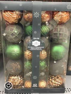 christmas ornaments are in a clear box on the shelf at costco, including green and gold baubles