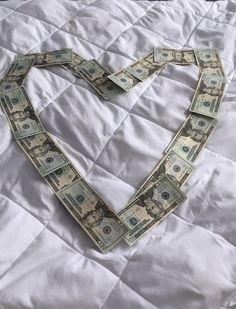 a heart made out of money on top of a bed