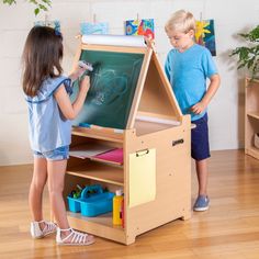 The transformative Desk to Easel Art Cart by Guidecraft is the perfect art space for your budding artist. Easily switch from a flat art desk to an angled drawing station with durable hinges that lock into place. The double-sided easel can be set up as a chalkboard, a write-on/wipe-off board, or used with the included paper roll, allowing multiple artists to work at the same time. Complete with a variety of storage compartments and included fabric bins, this unique art furniture provides the perf Table Easel Kids, Toddler Art Station Bedroom, Toddler Drawing Desk, Shaving Cream Desk Activity, Toddler Art Corner Living Room, Ikea Drawing Paper Roll, Easel Card With Drawer, Bureau D'art, Kids Art Easel