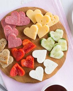 a wooden plate topped with heart shaped cheese and crackers