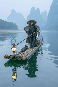 a man is standing on a boat in the water with two birds perched on it