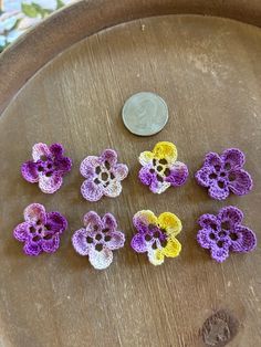 small crocheted flowers sitting on top of a wooden table next to a penny