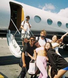 a group of people standing in front of an airplane with their arms around each other