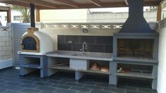 an outdoor pizza oven is built into the side of a building, with shelves on either side