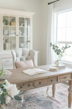 a living room with white furniture and flowers in vases on the coffee table next to it