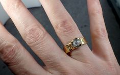 a person's hand with a gold ring on it and a black diamond in the middle