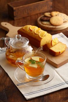 a glass tea cup filled with liquid next to sliced bread and cookies on a cutting board