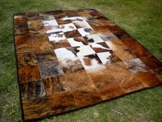 a brown and white patchwork rug sitting on top of grass