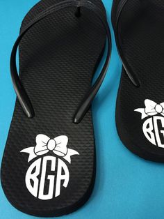 pair of monogrammed black flip flops with bow and monogramming on them