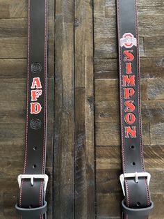 two black leather belts with red stitching on the sides and one has an american flag