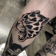 a black and white tattoo of a tiger on the left leg with other tattoos around it