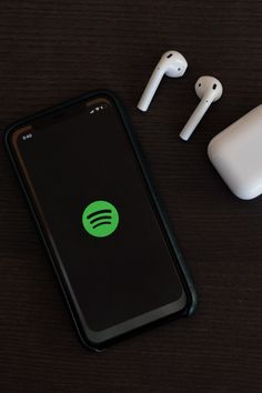 an iphone and ear buds sitting next to each other on top of a wooden table