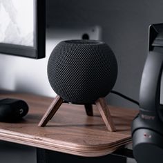 an apple home speaker sitting on top of a wooden table next to a computer monitor