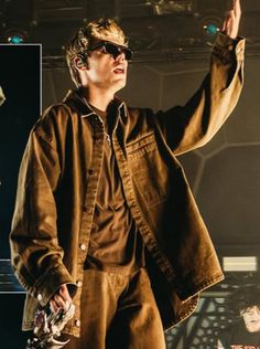 a man standing on top of a stage with his hand up in the air and wearing sunglasses