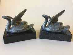 two statues of swans on black marble bases