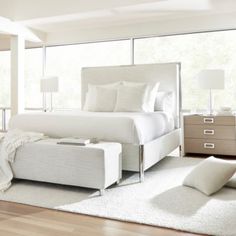 a white bed sitting in a bedroom on top of a hard wood floor next to a window