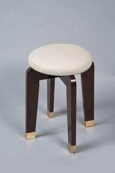 a small stool with a white seat and gold legs on a gray background in the style of art deco