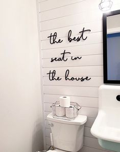 a white toilet sitting next to a sink in a bathroom under a framed wall art