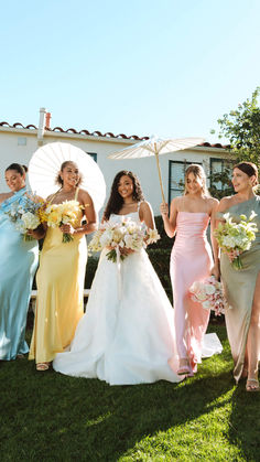 a group of bridesmaids holding umbrellas in the grass