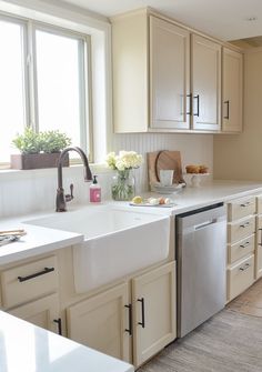 a clean kitchen with white cabinets and stainless steel dishwasher on the countertop