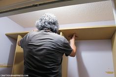 a man standing in front of a shelf with some paint on it's walls