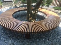 a circular wooden bench sitting next to a tree