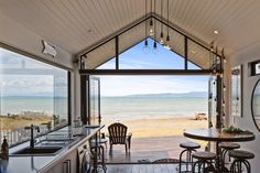 the inside of a beach house with an open kitchen and dining area overlooking the ocean