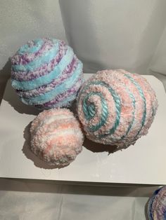 three balls of yarn sitting on top of a white surface