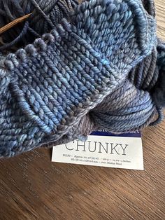 a skein of chunk yarn sitting on top of a wooden table next to a tag