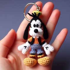 a hand holding a tiny crocheted keychain with a dog on it