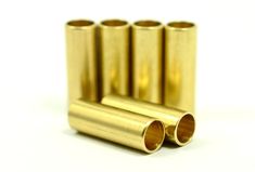 four brass tubes are lined up on a white surface