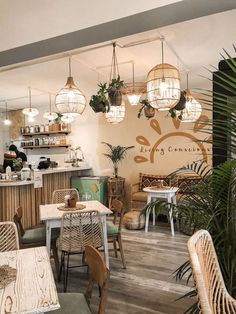 the inside of a restaurant with tables, chairs and plants hanging from the ceiling above