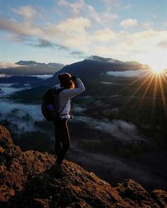 a person standing on top of a mountain looking at the sun