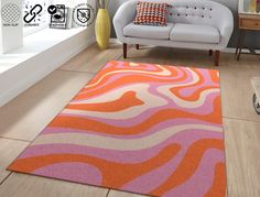 an orange and pink rug in a living room next to a white couch with pillows on it