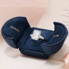 an engagement ring in a blue velvet box with the name harry written on it, sitting on top of a piece of paper