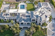 an aerial view of a large mansion with swimming pool in the center and landscaping around it