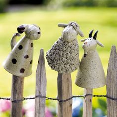 three ceramic sheep standing on top of a wooden fence