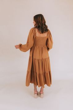 Get ready to fall head over heels for our Falling Faster Dress! This caramel-colored dress features delicate lace detailing and a charming tied bow on the front of the bodice. The smocked panel in the back ensures a comfortable and flattering fit, while the tiered skirt adds a whimsical touch. Complete with long, slightly puffed sleeves and a midi length, this dress also boasts a lace-trimmed neckline for an extra feminine touch. You'll be turning heads and feeling fabulous in this stunning dres Casual Dress With Smocked Back For Gatherings, Brown Smocked Bodice Dress For Brunch, Brown Fall Midi Dress For Brunch, Brown Midi Dress For Fall Brunch, Fall Dress With Smocked Bodice For Day Out, Fall Day Out Dress With Smocked Bodice, Fall Brunch Dress With Smocked Bodice, Brown Midi Dress With Smocked Bodice For Brunch, Casual Fall Midi Dress With Smocked Back