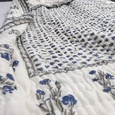 a white and blue bedspread with flowers on it